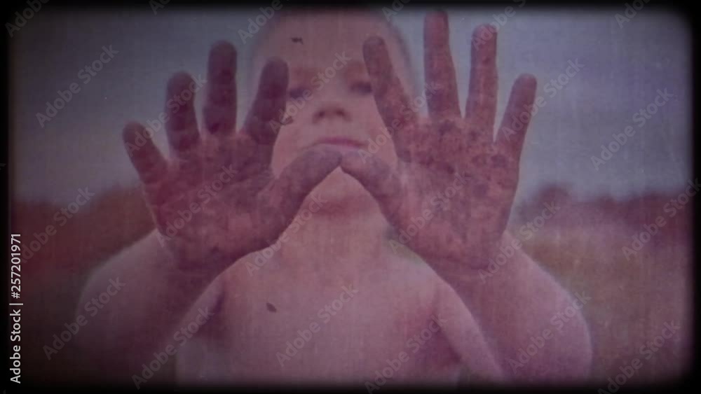 Family video archive. Retro camera 8 mm. Old film. Vintage. A happy child shows his hands dirty from the ground, a boy smeared in the mud, a merry childhood pastime