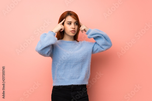 Young redhead woman over pink background having doubts and thinking © luismolinero