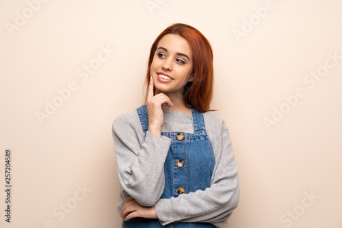 Young redhead woman over isolated background thinking an idea while looking up