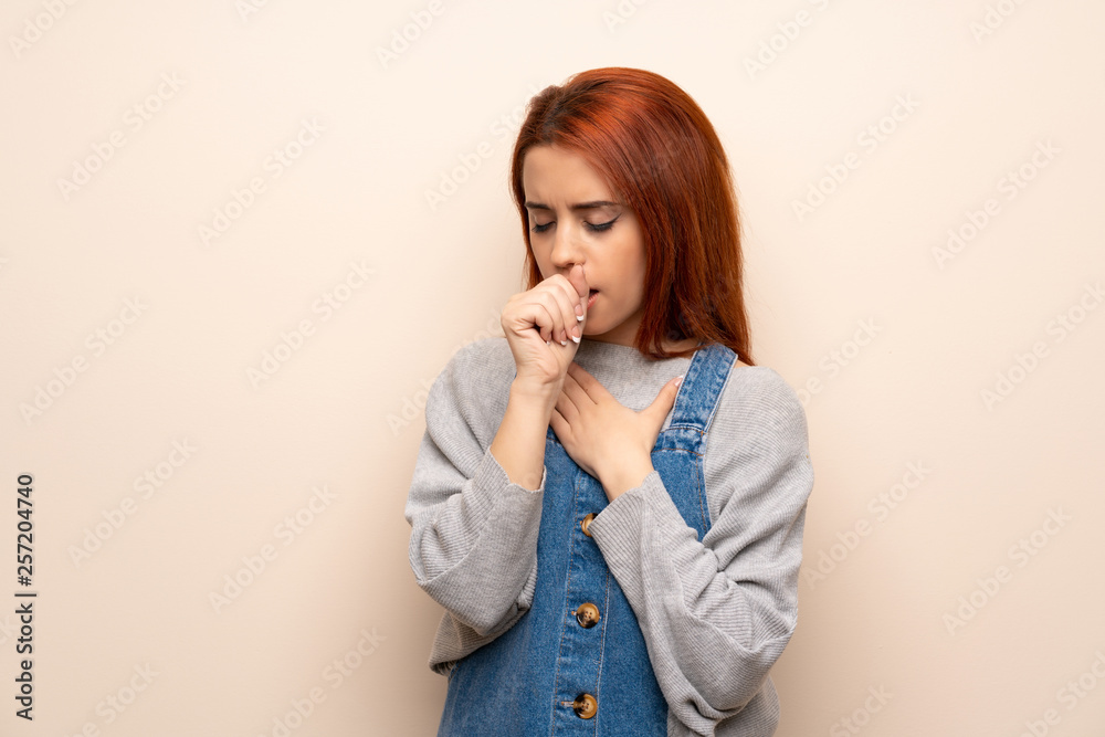 Young redhead woman over isolated background is suffering with cough and feeling bad Young redhead woman over isolated background is suffering with cough and feeling bad