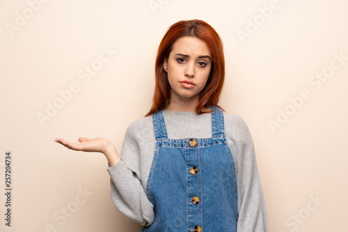 Young redhead woman over isolated background serious while holding copyspace imaginary