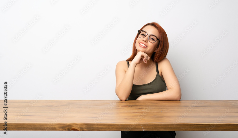 Young redhead woman at desk with glasses and happy Young redhead woman at desk with glasses and happy