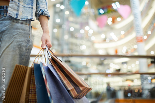 Close-up of unknown woman in jeans carrying shopping bags in mall, she doing shopping alone photo