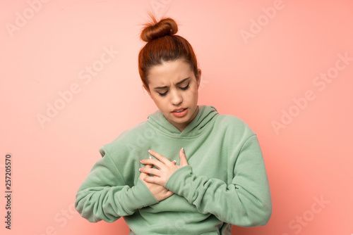 Young redhead woman with sweatshirt having a pain in the heart © luismolinero