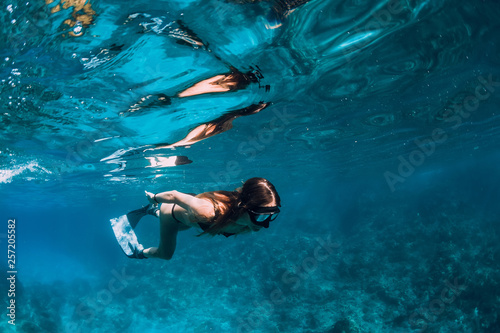 Young woman freediver with fins swim underwater ocean