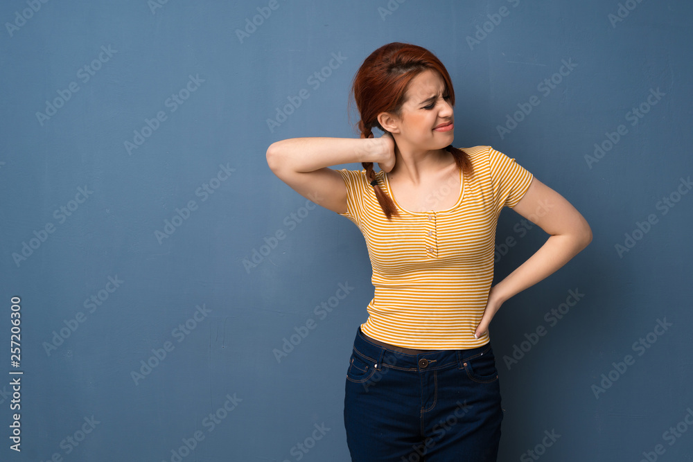 Young redhead woman over blue background with neckache