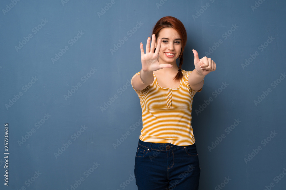 Young redhead woman over blue background counting six with fingers Young redhead woman over blue background counting six with fingers