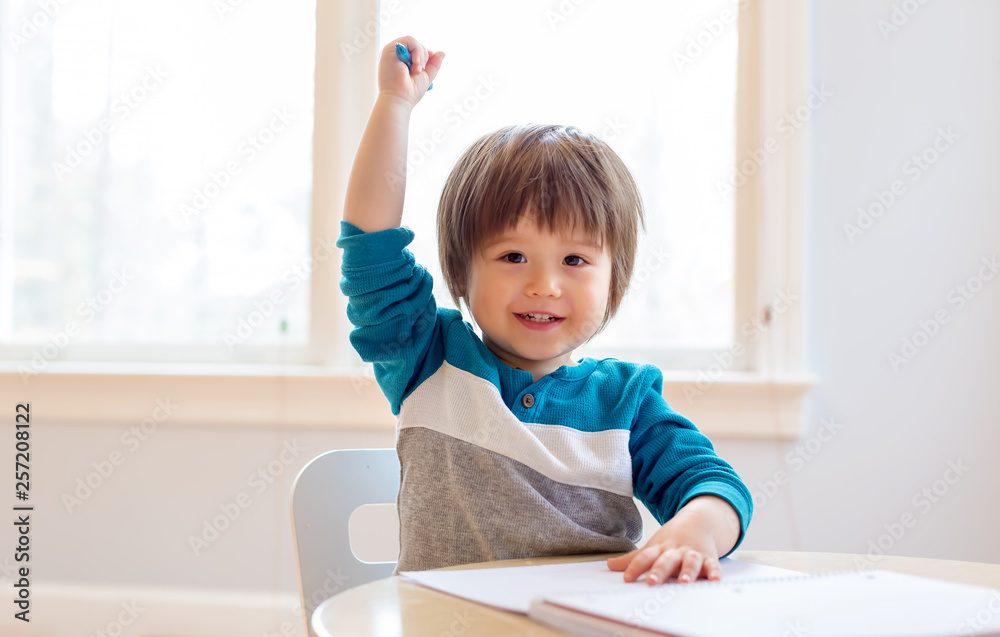 Happy excited toddler raising his hand high