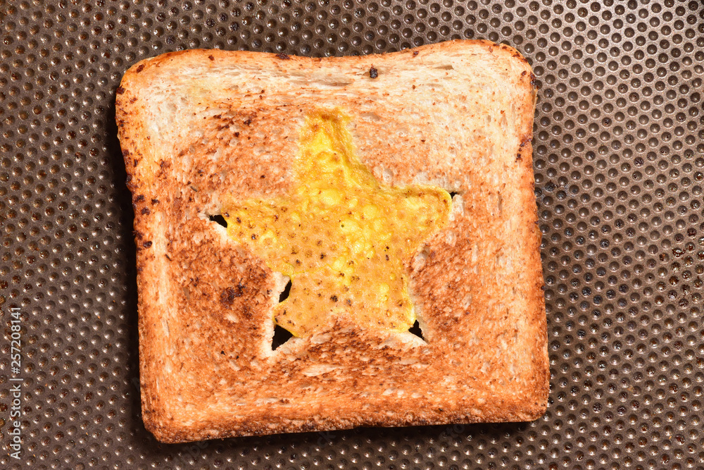 Roasting bread toasts with a star-shaped middle and omelette filled with egg to create a sandwich. Bread is fried for sandwiches in a pan with a non-stick coating, close-up