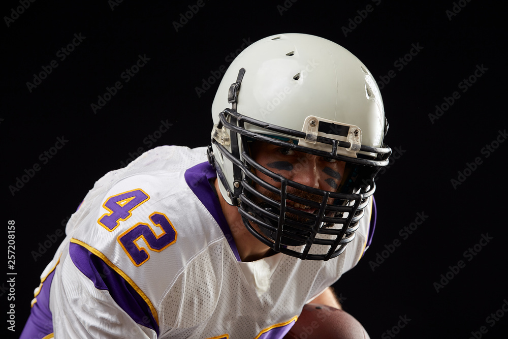 Fototapeta premium Close up portrait of American football sportsman player in action on black background. Sport concept.