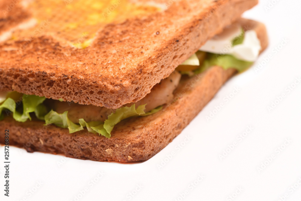 Appetizing toasted bacon sandwich and leaf of lettuce, on a white background. Close-up Appetizing toasted bacon sandwich and leaf of lettuce, on a white background. Close-up