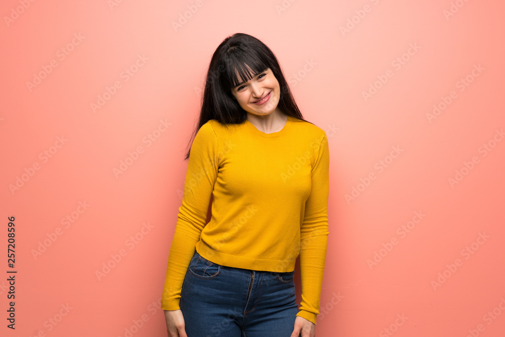Woman with yellow sweater over pink wall smiling Woman with yellow sweater over pink wall smiling