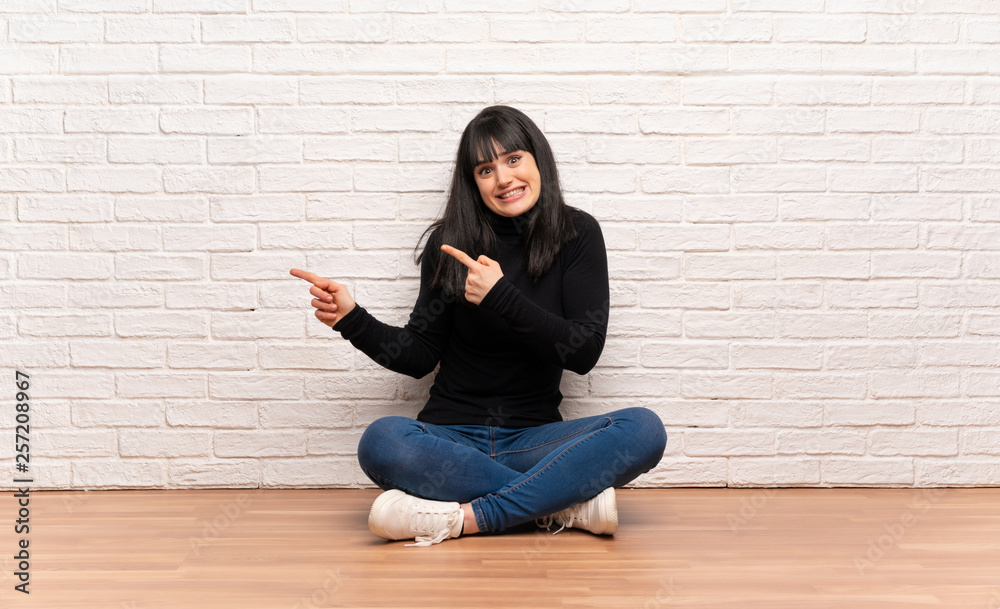 Woman sitting on the floor frightened and pointing to the side Woman sitting on the floor frightened and pointing to the side