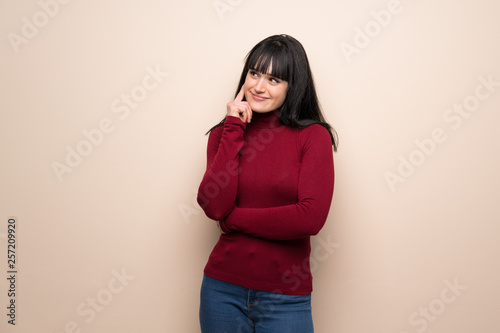 Young woman with red turtleneck thinking an idea while looking up