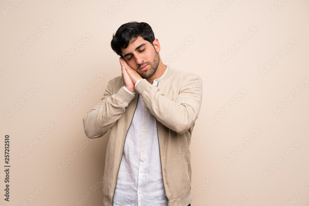 Young man over isolated wall making sleep gesture in dorable expression Young man over isolated wall making sleep gesture in dorable expression