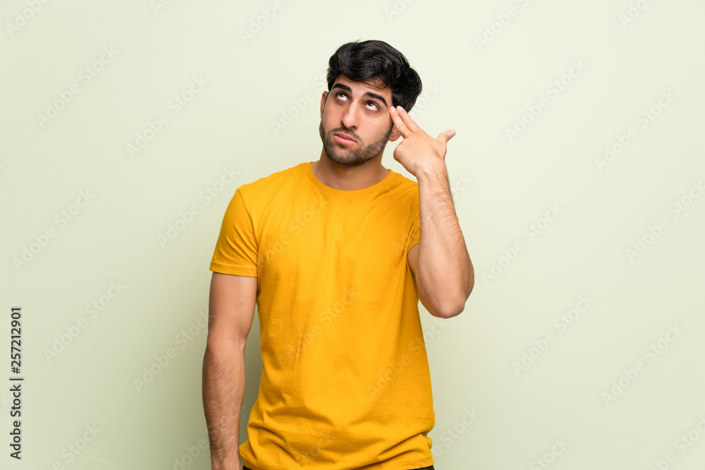 Young man over pink wall with problems making suicide gesture Young man over pink wall with problems making suicide gesture