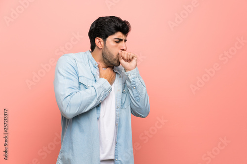 Young man over pink wall is suffering with cough and feeling bad photo