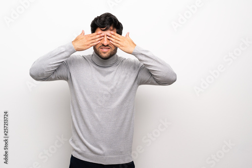 Young man over isolated white wall covering eyes by hands
