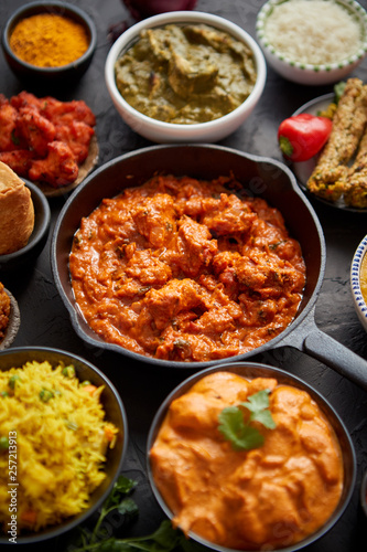 Various Indian dishes on a table. Spicy chicken Tikka Masala in iron pan
