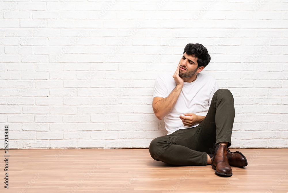 Young man sitting on the floor with toothache Young man sitting on the floor with toothache
