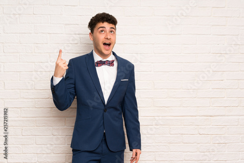 Man in suit and bow tie pointing up and surprised