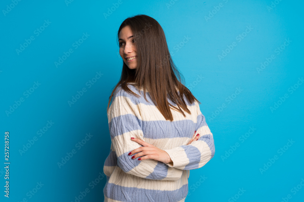 Young woman over blue wall with arms crossed Young woman over blue wall with arms crossed