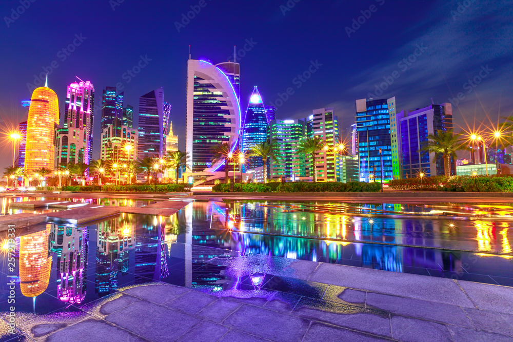Fototapeta premium Capital of Qatar. Colorful Doha West Bay high rises illuminated at night reflections in downtown park. Scenic towers of Doha skyline, Middle East, Arabian Peninsula in Persian Gulf. Violet colors shot