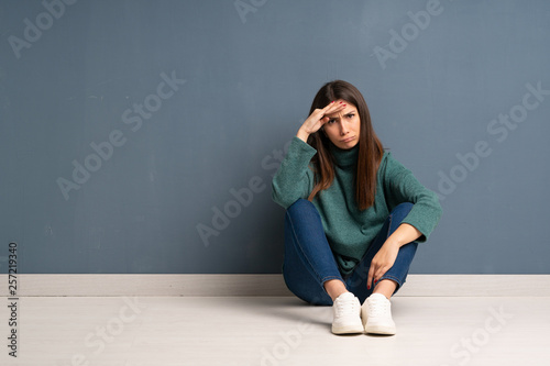 Young woman sitting on the floor looking far away with hand to look something