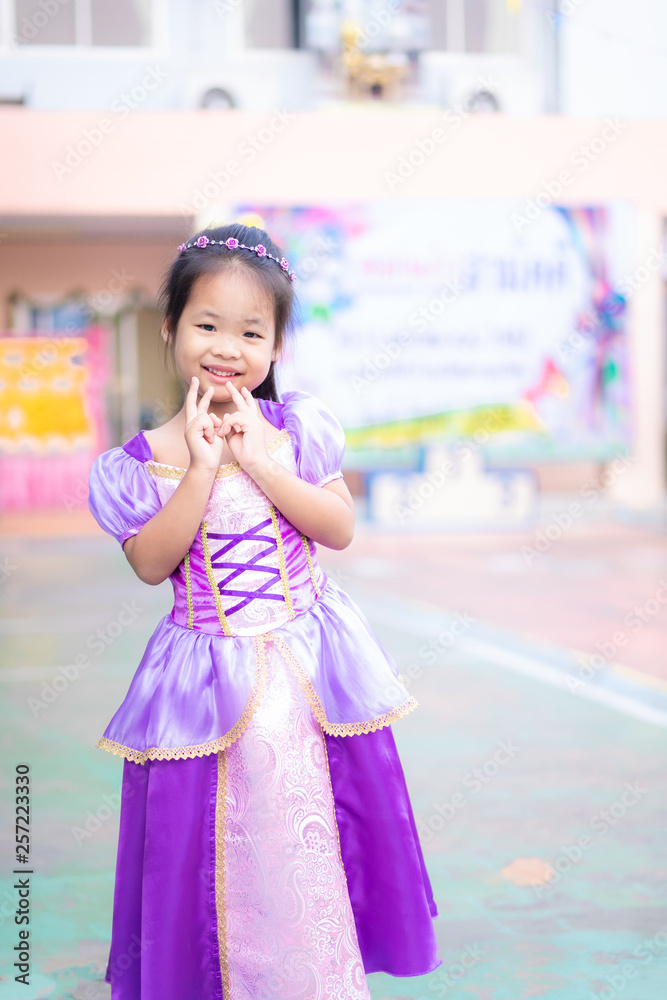 Portrait of cute smiling little girl in princess costume standing in school