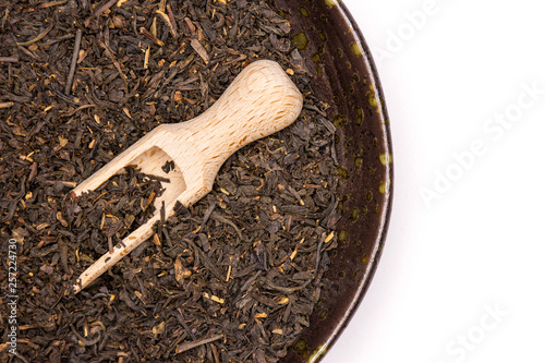 Photos Lot of pieces of dry black tea earl grey in a grey ceramic bowl with wooden scoo