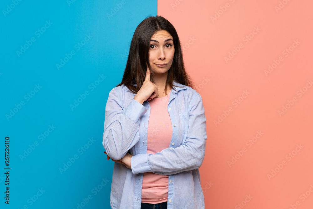Young woman over pink and blue wall thinking Young woman over pink and blue wall thinking