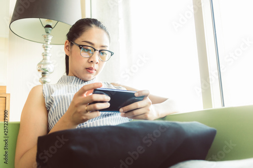 Woman concentrate on playing mobile game on the sofa.