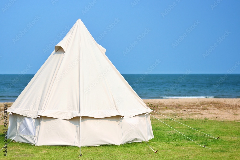 white tent on green grass at beach with crystal sea water and blue sky