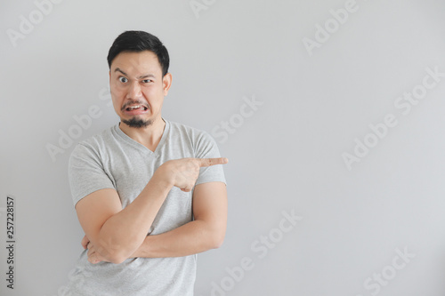 Hate face of man in grey t-shirt with hand point on empty space. photo