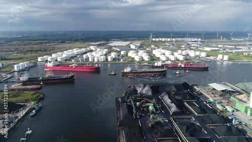 Aerial arriving at of busy harbor area oil depot is an industrial facility for storage of petrochemical products showing tankers and tugs maneuvering the congested port waters 4k high resolution photo