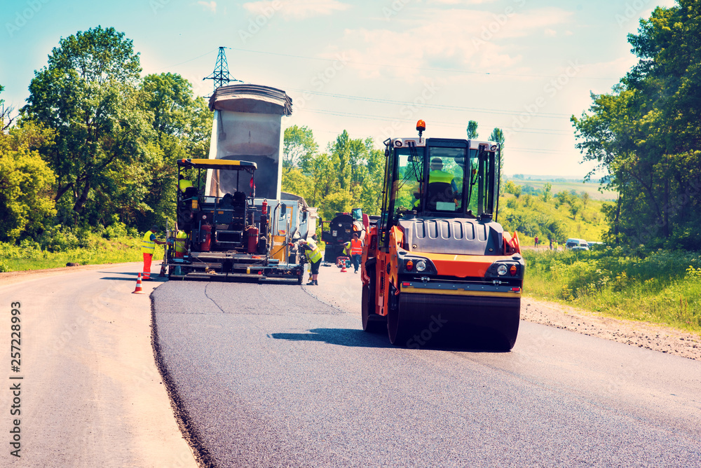 industrial landscape with rollers that rolls a new asphalt in the roadway. Repair, complicated transport movement.