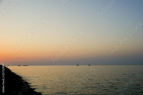Distant Cargo Ships in a calm sea at evening