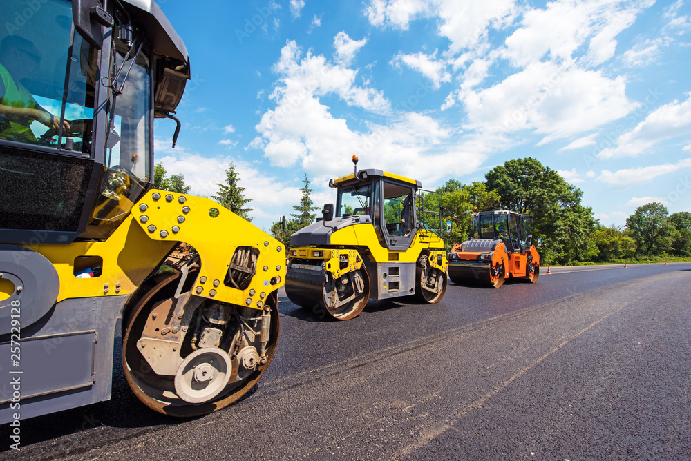 industrial landscape with rollers that rolls a new asphalt in the roadway. Repair, complicated transport movement.