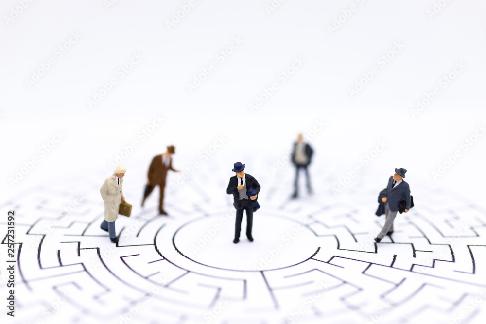 Miniature people : Businessmen standing on maze map and looking for a solution with teamwork. Image use for solve problems and new idea concept. Miniature people : Businessmen standing on maze map and looking for a solution with teamwork. Image use for solve problems and new idea concept.