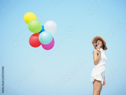 Happy Asian woman holding colorful of balloons over blue sky background,copy space.