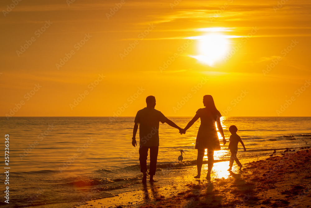 family walking along beach at sunset