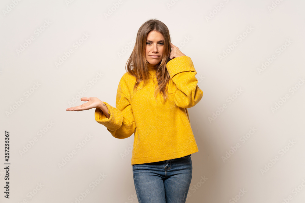 Woman with yellow sweater over isolated wall making the gesture of madness putting finger on the head Woman with yellow sweater over isolated wall making the gesture of madness putting finger on the head