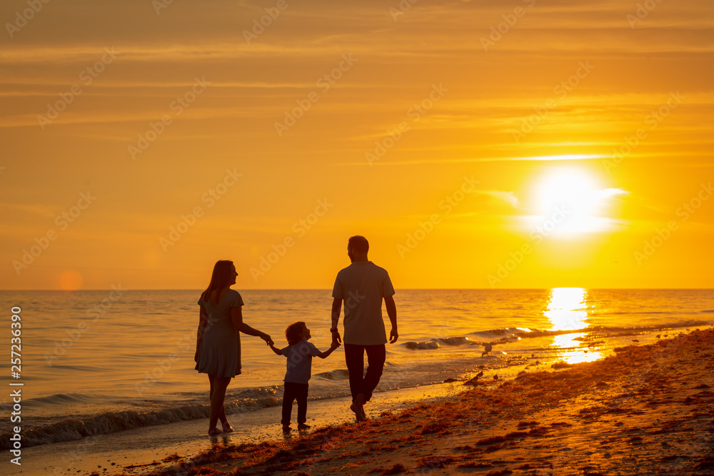 family walking along Florida beach at sunset