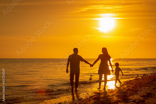 family walking along beach at sunset