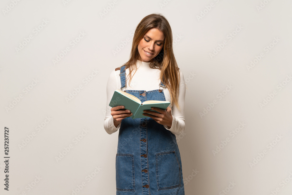 Beautiful woman over isolated white wall holding a book and enjoying reading Beautiful woman over isolated white wall holding a book and enjoying reading