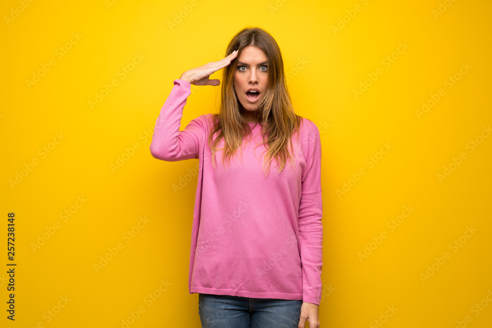 Woman with pink sweater over yellow wall has just realized something and has intending the solution Woman with pink sweater over yellow wall has just realized something and has intending the solution