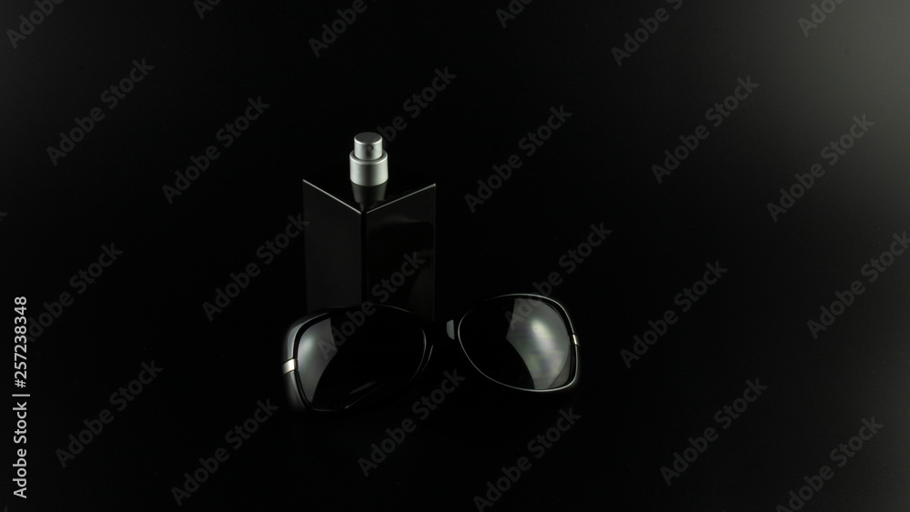parfume and glasses on black background