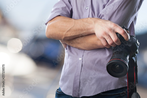 Young man holds modern digital black camera