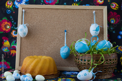 Easter decoration with white and blue eggs on painted textile background with corkboard.  Easter still life. Easter eggs, Easter service. Easter decor. 