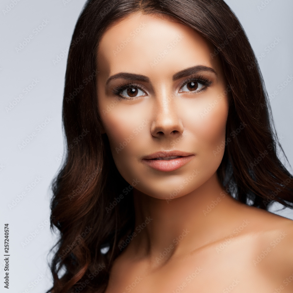 portrait of beautiful young woman with naked shoulders, on bright grey portrait of beautiful young woman with naked shoulders, on bright grey